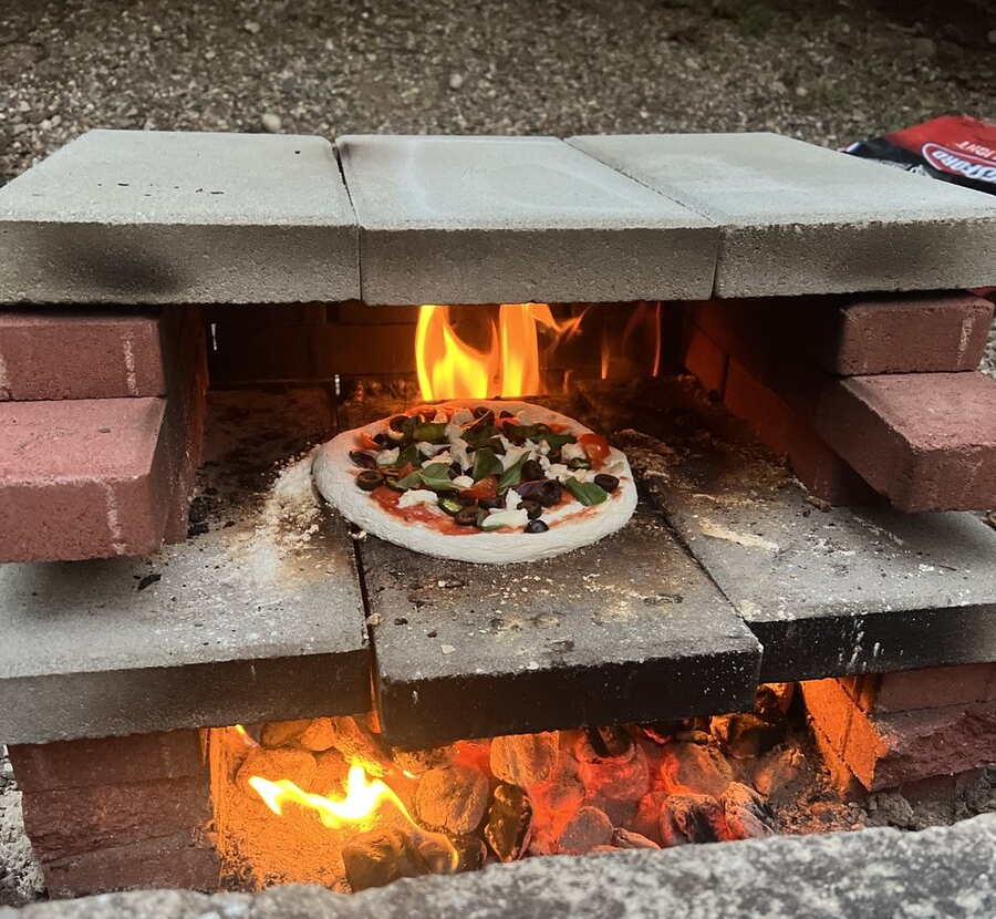 Pizza in the pizza oven, over a roaring fire